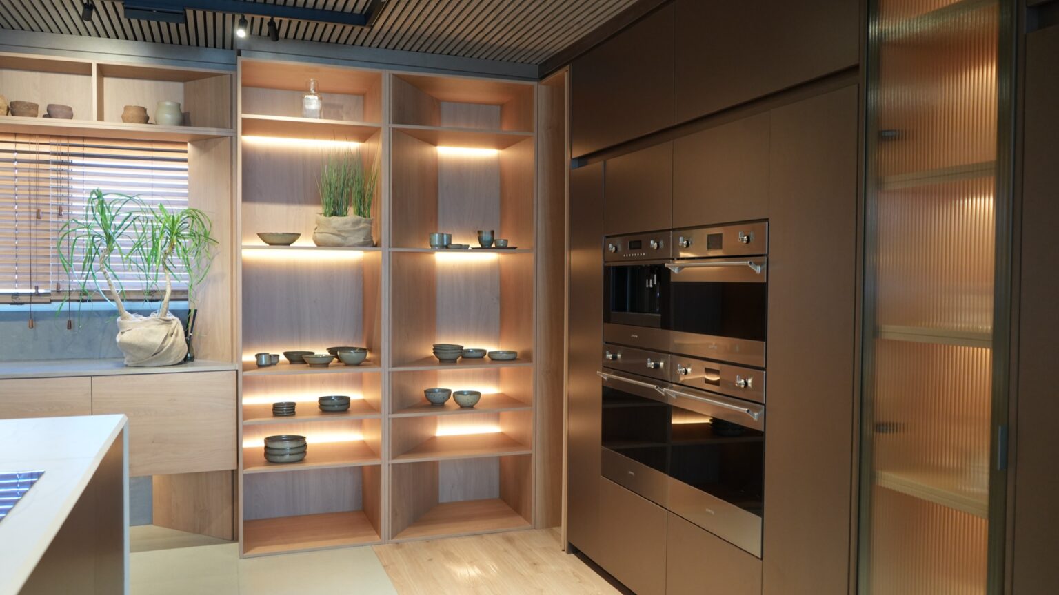 Estantería iluminada y hornos empotrados en la cocina