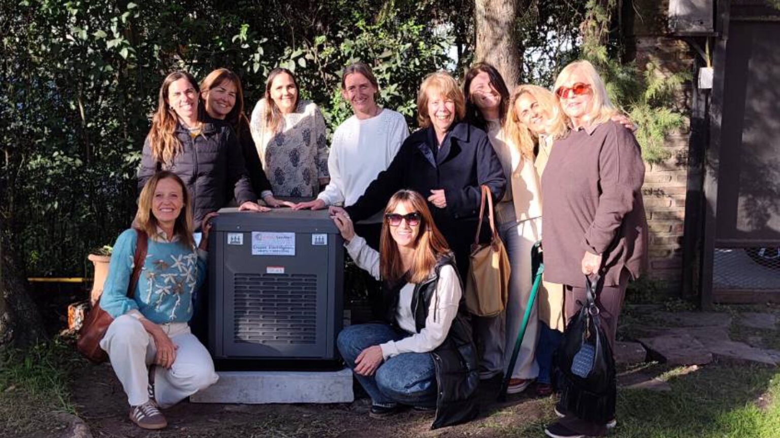 El grupo electrógeno donado, en la Casa de Niños de Somos UPA, rodeado por las mujeres de Amigos del Pilar.